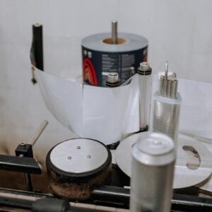photo by cottonbro studio Detailed view of a brewery machinery used for labeling beer cans in an industrial setting.
