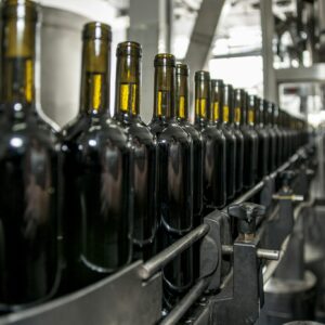 Rows of wine bottles on a production line in an industrial setting.
